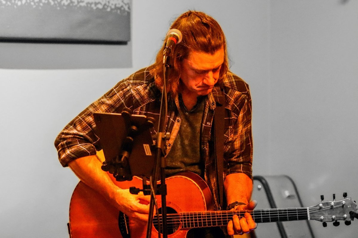 Denny Menter performing live with an acoustic guitar