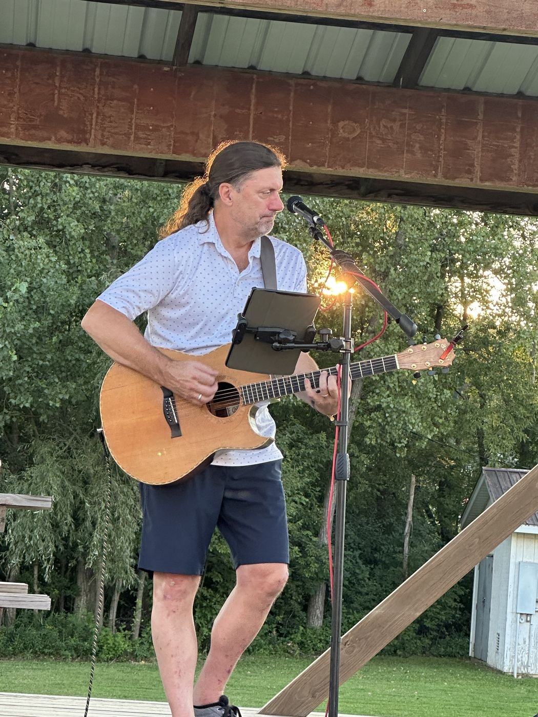 Denny Menter performing acoustic guitar outdoors at sunset