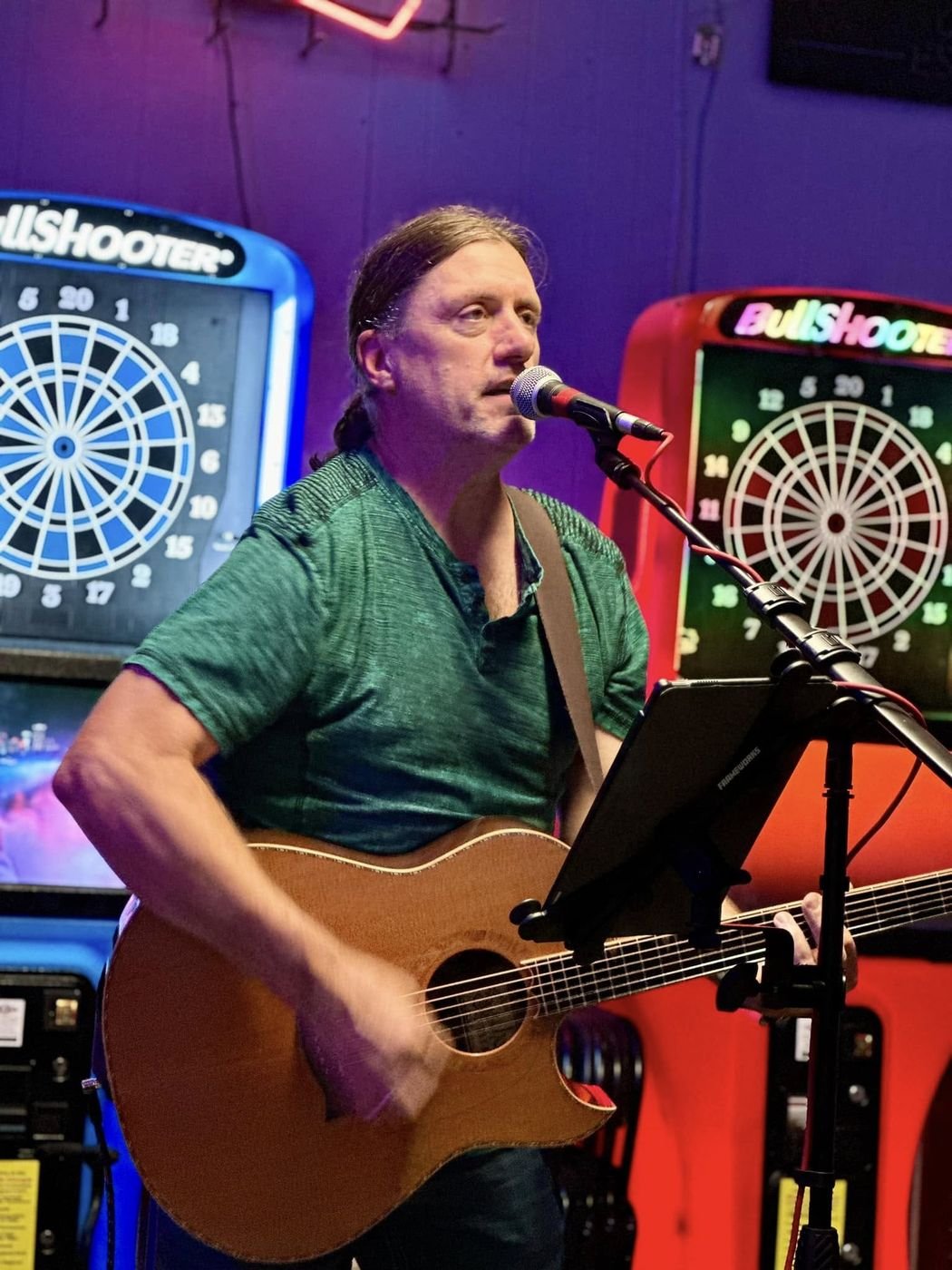 Denny Menter performing acoustic guitar at a bar
